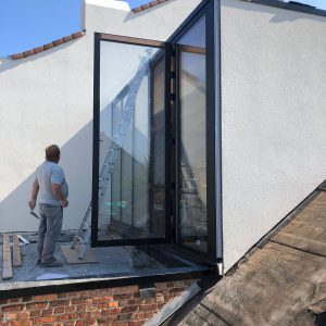 ouvrier sur le toit d'une maison et un en-dessous de l'échelle
