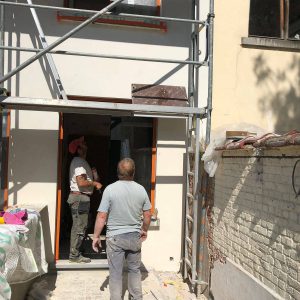 ouvrier sous un échafaudage devant une maison en rénovation